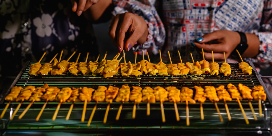 Kvinder tilbereder moo satay på grill