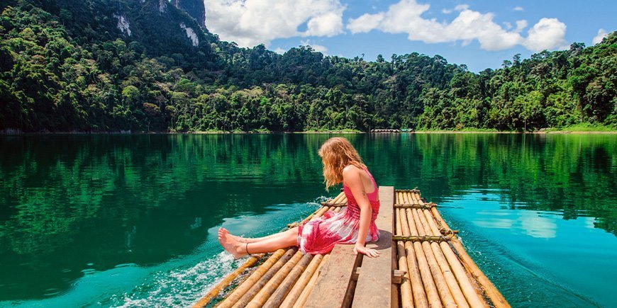 Ung pige, der sidder ved søen i Khao Sok Nationalpark i Thailand