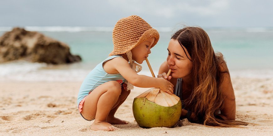 Ung kvinde og barn på en strand i Thailand