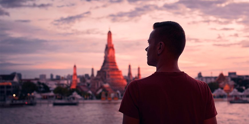 Mand står foran Wat Arun i Thailand ved solnedgang