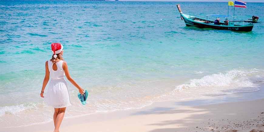 Kvinde går på stranden i Thailand med nissehue på