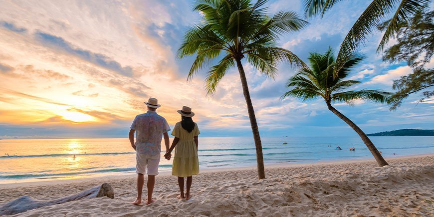 Par holder i hånd og kigger på solnedgangen på strand på Phuket