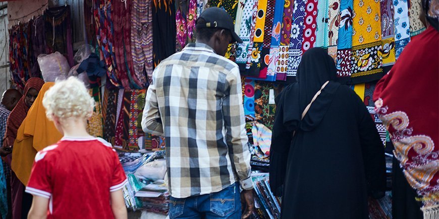 Dreng går blandt de lokale på marked i Stone Town